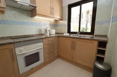 a kitchen with wooden cabinets and a sink and a dishwasher at São Rafael Beach Apartment 92A, Albufeira - Algarve in Albufeira