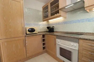 a kitchen with wooden cabinets and a stove top oven at São Rafael Beach Apartment 92A, Albufeira - Algarve in Albufeira