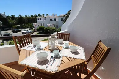 a wooden table with plates and cups on a balcony at São Rafael Beach Apartment 92A, Albufeira - Algarve in Albufeira