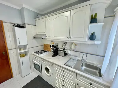 a kitchen with white cabinets and a sink at Amazing Ocean View Apt Steps from the Beach in Quarteira