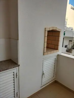 a kitchen with white cabinets and a wall with a window at T2 Infante AC wifi Garagem 50m Praia in Quarteira
