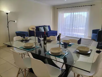 a dining room with a glass table and chairs at T2 Infante AC wifi Garagem 50m Praia in Quarteira
