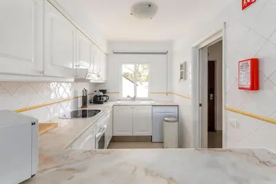 a kitchen with white cabinets and a sink and a window at Moradia Olhos de Água - 3 quartos - 6 camas in Albufeira