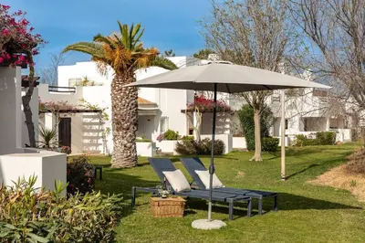 an umbrella and lounge chairs in the grass at Moradia Olhos de Água - 3 quartos - 6 camas in Albufeira