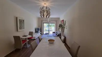 a living room with a dining room table and a chandelier at Splendide Appartement Standing Casa Biblos en Famille ou en Amoureux in Albufeira