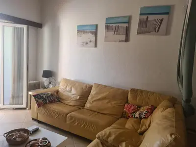 a living room with a brown couch and pictures on the wall at Vilamoura Alecrim in Vilamoura