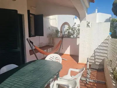 a patio with a table and chairs and a hammock at Vilamoura Alecrim in Vilamoura