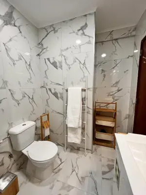 a bathroom with a toilet and a marble wall at Julias Beach Retreat in Quarteira