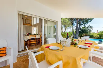 a dining room with a yellow table and white chairs at Villa Bolota in Albufeira