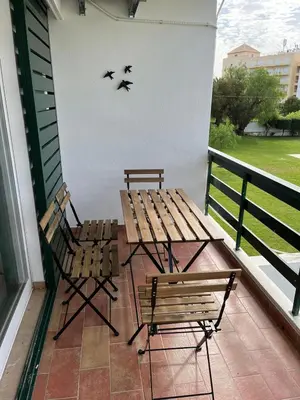 two benches and a table on a porch with birds flying at Vilamoura Neptuno Apartment in Vilamoura