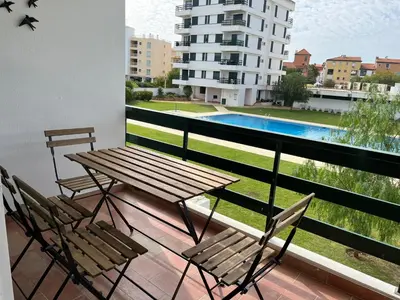 a balcony with a table and chairs and a swimming pool at Vilamoura Neptuno Apartment in Vilamoura