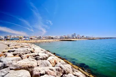 a beach with rocks and people on the water at Luxury 3-Bed Penthouse with Ocean Views, Terrace & Pool in Quarteira