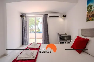a bedroom with a white bed with red pillows and a window at #265 Charming Villa Sam in Albufeira