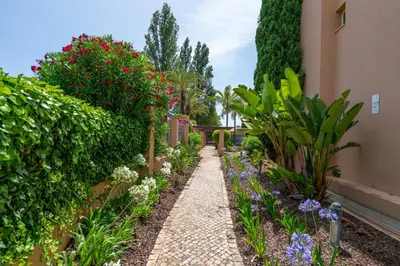 a garden with palm trees and flowers in front of a building at Coastal Greens by Seareen in Quarteira