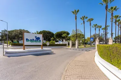 a sign in the middle of a road with palm trees at Balaia Golf Poolside Retreat - Superior 2 bed villa in Albufeira