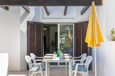 a white table with chairs and a yellow umbrella at Balaia Golf Poolside Retreat - Superior 2 bed villa in Albufeira