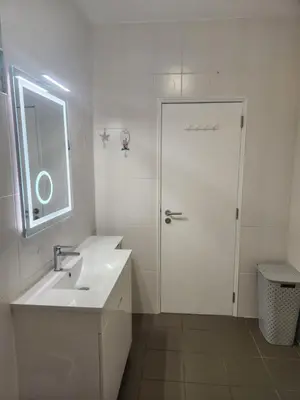 a white bathroom with a sink and a door at L&J Ocean View Apartment in Albufeira