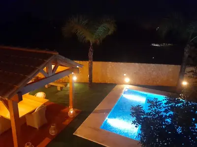 a swimming pool at night with a table and palm trees at Real Village in Quarteira