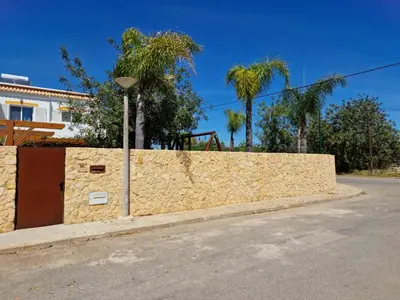 a stone wall next to a street with palm trees at Real Village in Quarteira