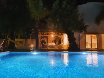 a swimming pool at night with a table and chairs at Real Village in Quarteira