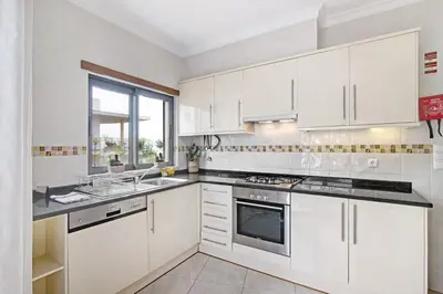 a white kitchen with white cabinets and a window at Flat with Pool Marina and Sea View in Albufeira