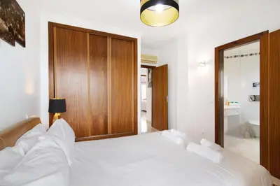 a bedroom with a white bed with a wooden cabinet at Flat with Pool Marina and Sea View in Albufeira