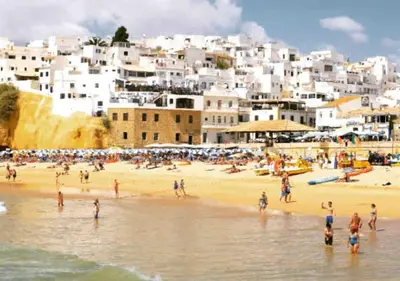 a group of people on a beach in front of a city at Studio with great sea view, near the beach, with AC and pools in Albufeira