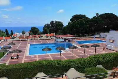a view of a pool with umbrellas and the ocean at Studio with great sea view, near the beach, with AC and pools in Albufeira