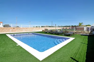 a swimming pool on a lawn with a table and chairs at Villa Flora in Algoz