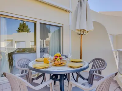 a blue table with a bowl of fruit and an umbrella at AL - Apartamento Falésia Terrace in Vilamoura