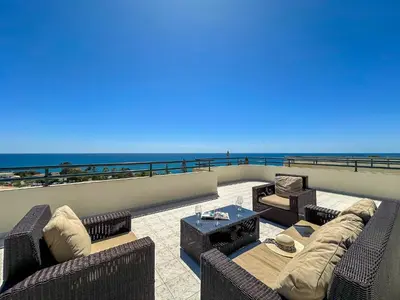 a living room with couches and a view of the beach at Luxury Penthouse wStunning Sea Views, walk to Galé Beach Albufeira in Albufeira