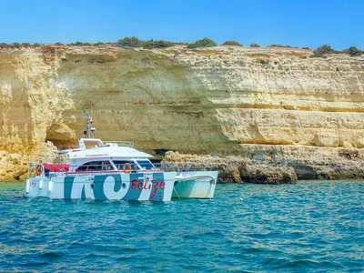 a boat in the water next to a cliff at Luxury Penthouse wStunning Sea Views, walk to Galé Beach Albufeira in Albufeira