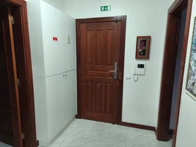 a hallway with a wooden door and a refrigerator at Quarteira Apartamento T2 - Oceanides in Quarteira