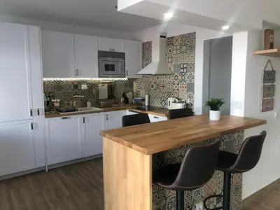 a kitchen with white cabinets and a wooden counter top at Vila Luisa Anabela Piscine et Jacuzzi in Albufeira