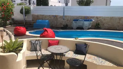 a patio with chairs and a table next to a pool at Vila Luisa Anabela Piscine et Jacuzzi in Albufeira