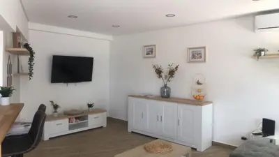 a living room with a tv on a white wall at Vila Luisa Anabela Piscine et Jacuzzi in Albufeira