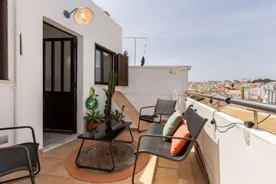 a balcony with chairs and tables on a building at Casinha da Jade in Albufeira