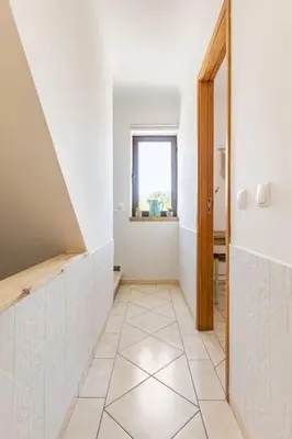 a hallway with a white tile floor and a window at Casinha da Jade in Albufeira