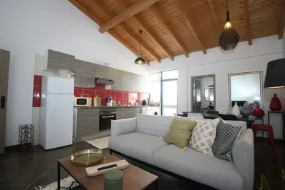 a living room with a couch and a kitchen at Birdy House in Faro